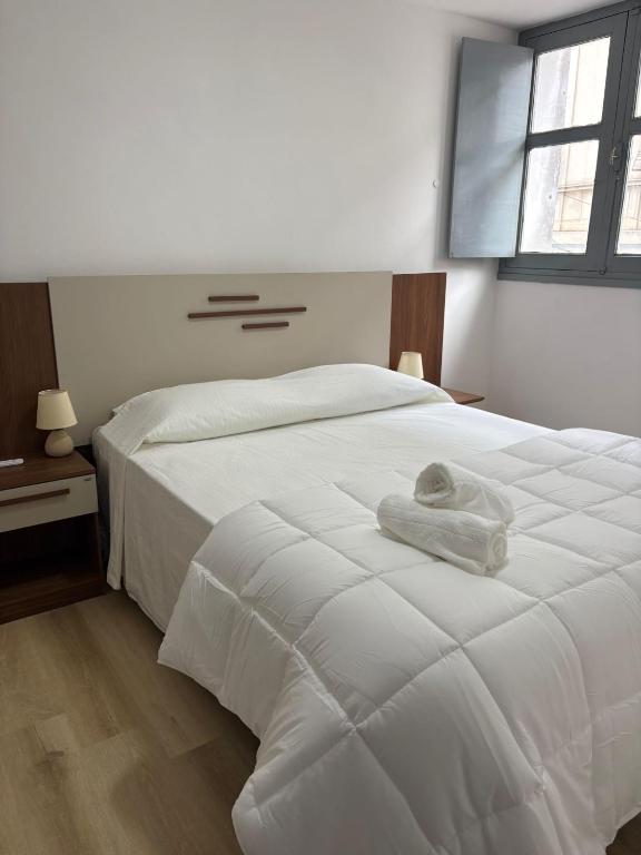a bedroom with a white bed with a towel on it at Apartamentos Plaza Minas in Minas
