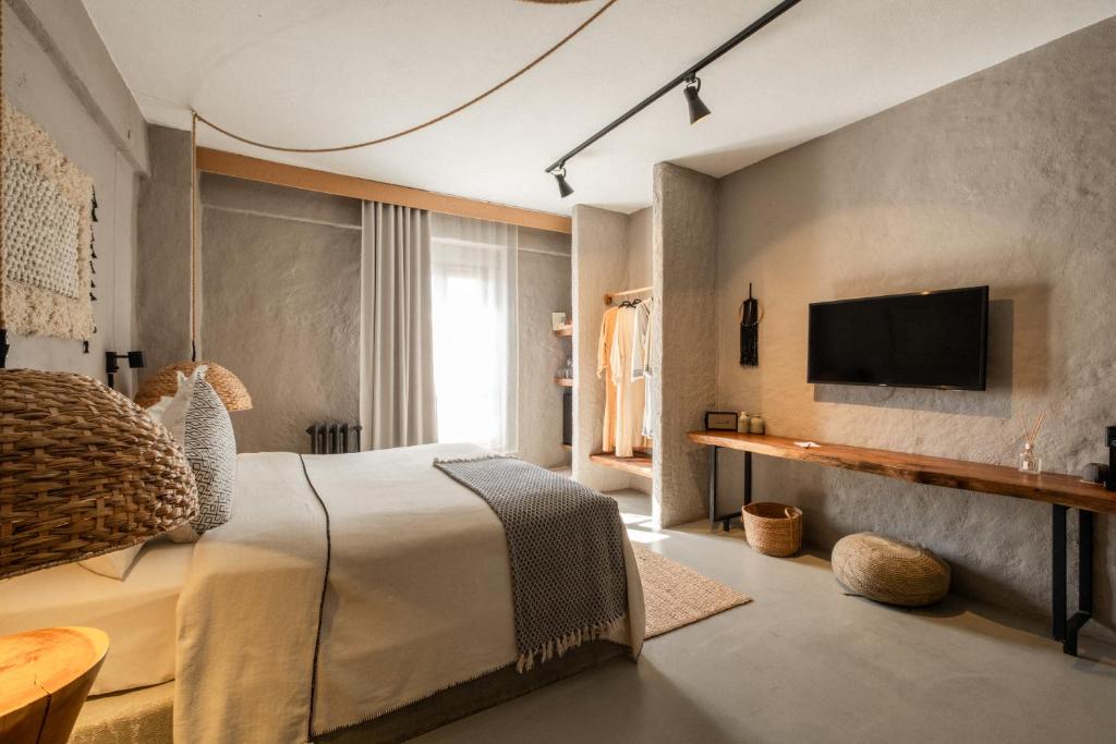 a bedroom with a bed and a tv on a wall at GAIA ALAÇATI in Alaçatı