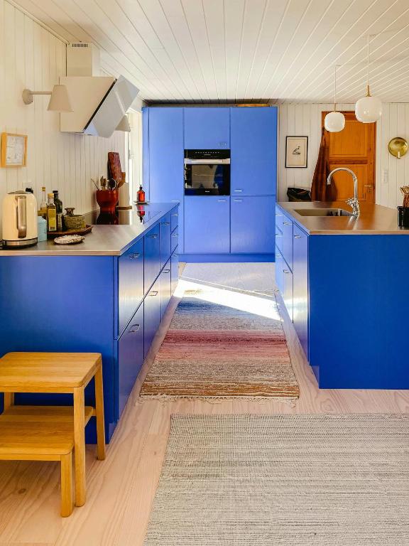 a kitchen with blue cabinets and a sink and a table at Thatched Hideaway At Svinkløv Forest Edge in Fjerritslev