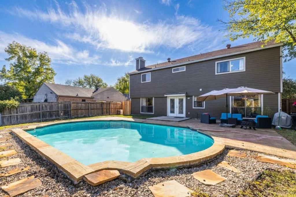a swimming pool in the backyard of a house at Spacious 4BR Home with Pool BBQ & Games in Grand Prairie