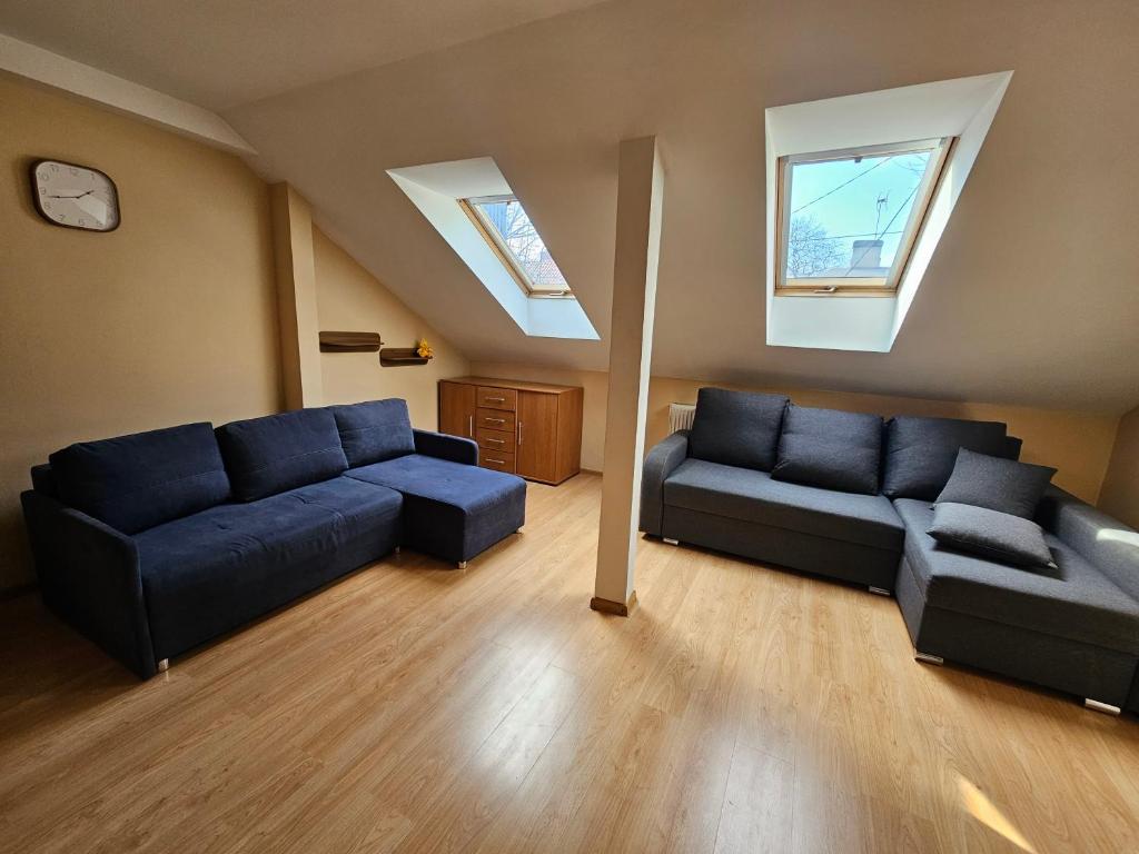 a living room with two blue couches and two windows at Cudowne poddasze in Piotrków Trybunalski