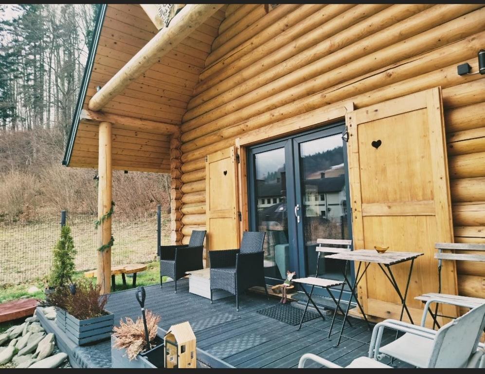 a cabin with a deck with chairs and a table at Chatka pod lasem Szczyrk Domek z jacuzzi in Szczyrk