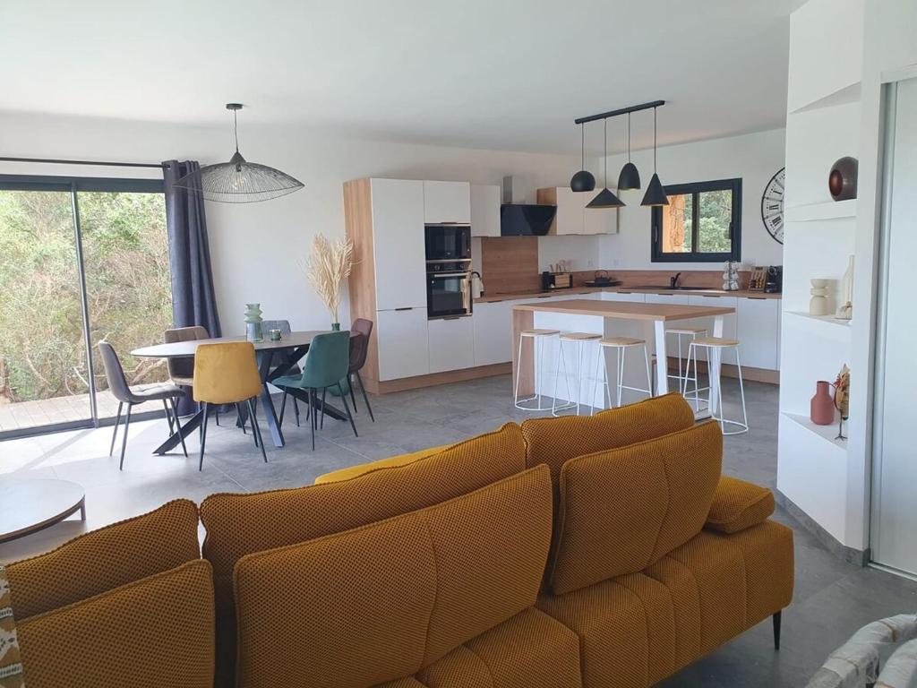a living room and kitchen with a couch and a table at Villa Cocooning, Piscine privative à Figari in Figari