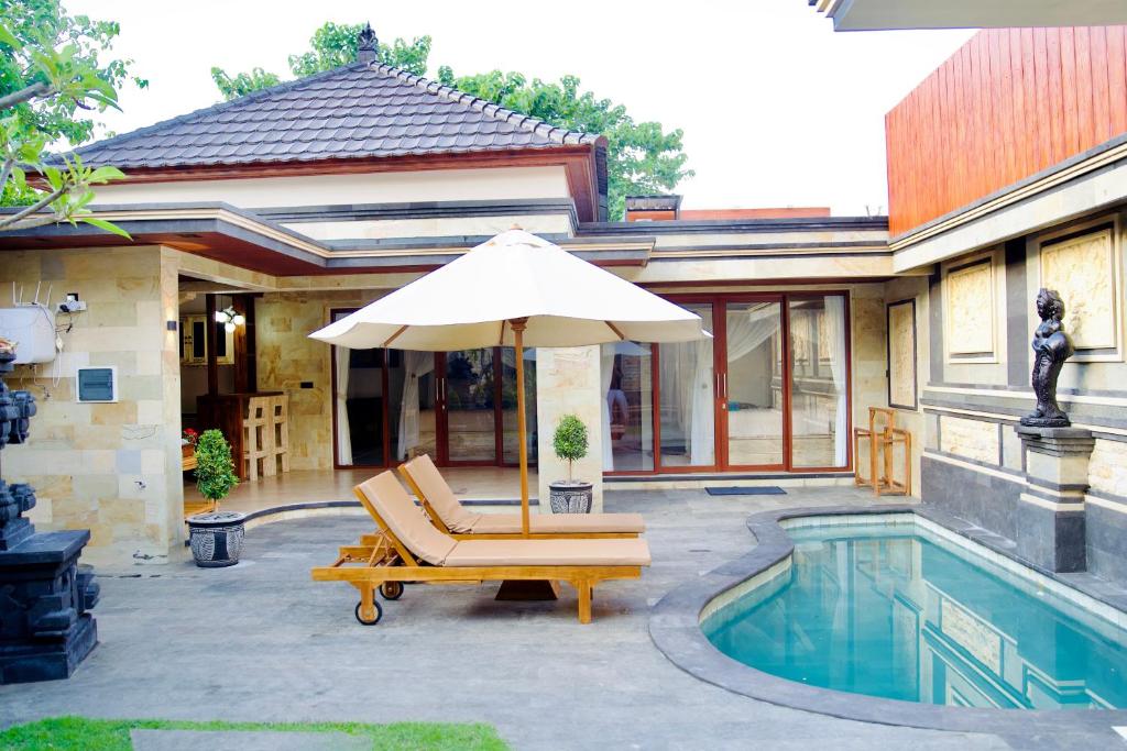 a pool with a chair and an umbrella next to a house at Inaya Private Pool Villa in Ambat