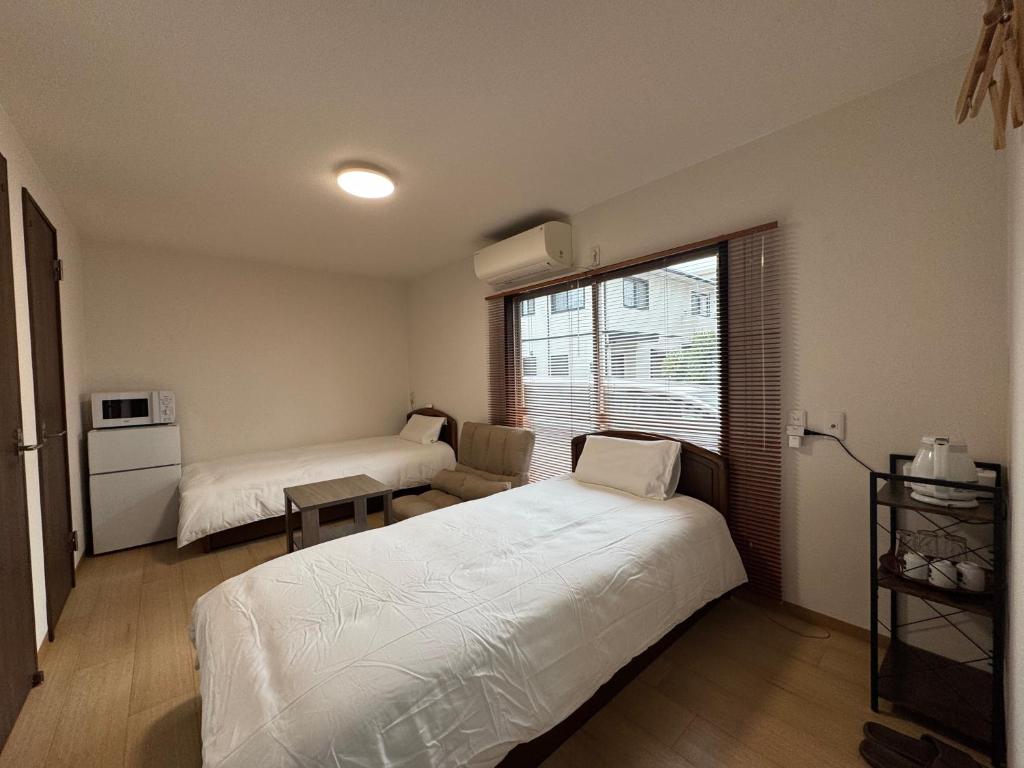 a bedroom with two beds and a window at KIX Nest in Izumi-Sano