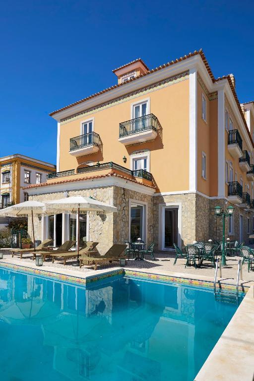 a villa with a swimming pool in front of a building at Estoril Boutique Hotel - Adults Only in Estoril