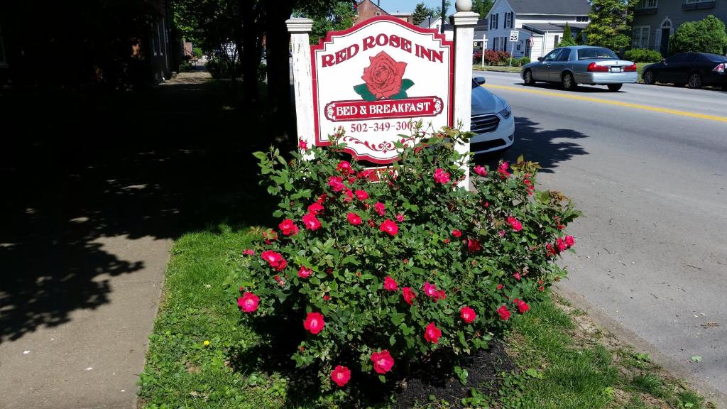 a sign with pink flowers next to a street at Red Rose Inn Bed and Breakfast in Bardstown