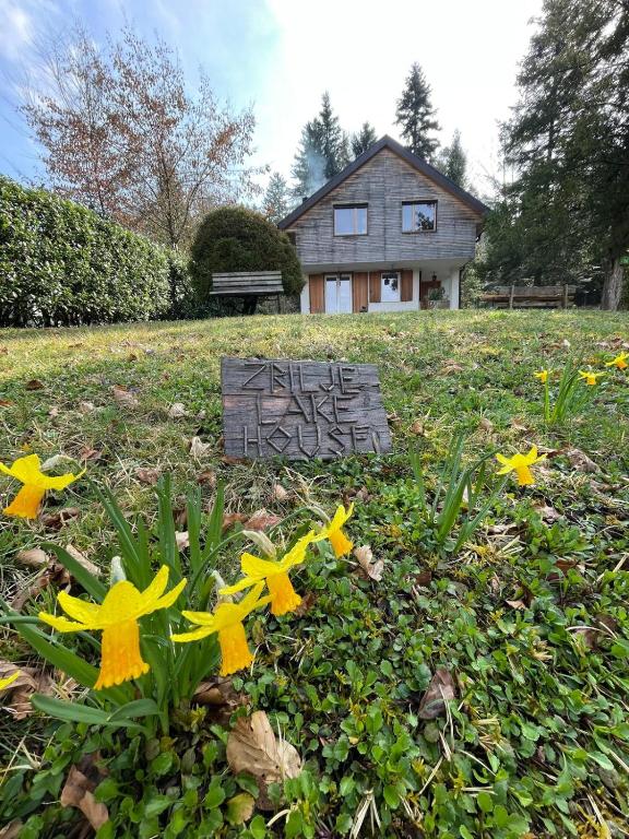 a sign in the grass with flowers in front of a house at Zbilje Lake house in Medvode