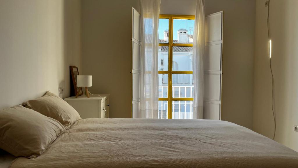 a bedroom with a bed and an open window at Villa Alhelí del Aljarafe in Mairena del Aljarafe