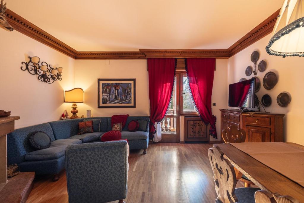 a living room with a blue couch and red curtains at Casa Amalia, with panoramic terrace in Cortina dʼAmpezzo