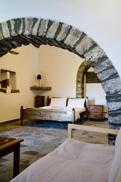 a bedroom with two beds and a stone wall at Anéza house tinos in Skaládhos