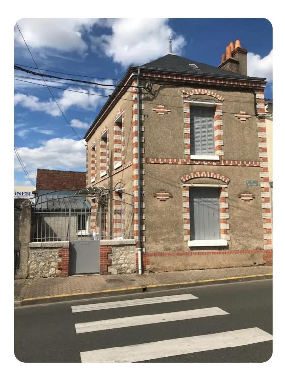a brick building with a crosswalk in front of a street at Maison des chateaux in Bléré