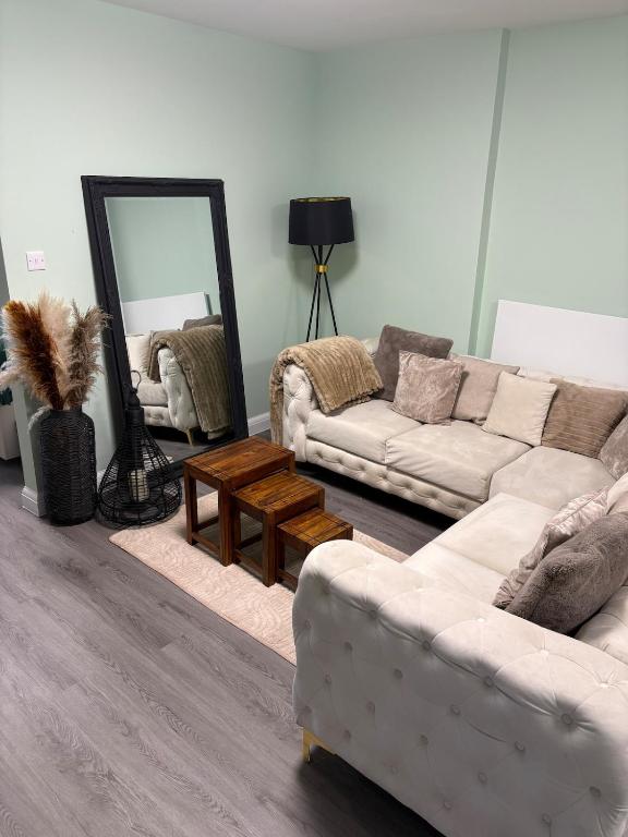 a living room with two white couches and a mirror at Petite Apartment in Denham in Denham