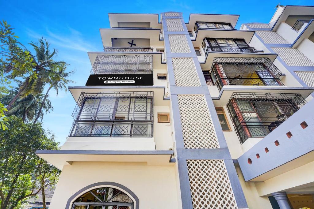 a tall white building with a sign on it at Super Townhouse Calangute Formerly Hotel Horizon in Goa