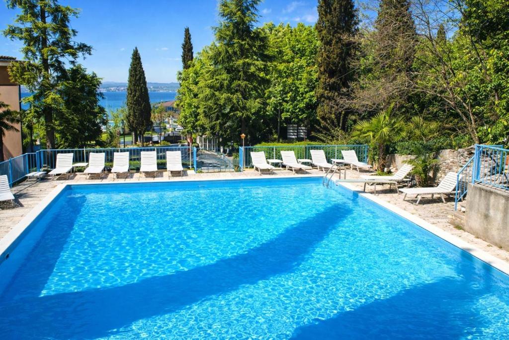a swimming pool with chaise lounge chairs and the ocean at Hotel Broglia in Sirmione