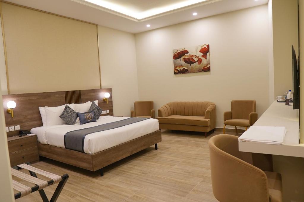 a hotel room with a bed and a couch and chairs at RT Serene Hotel - Larkana in Lāhori