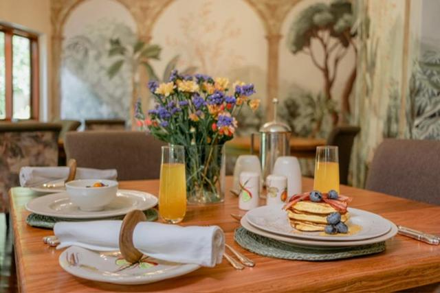 a wooden table with plates of food and flowers on it at Tuli House in Harare