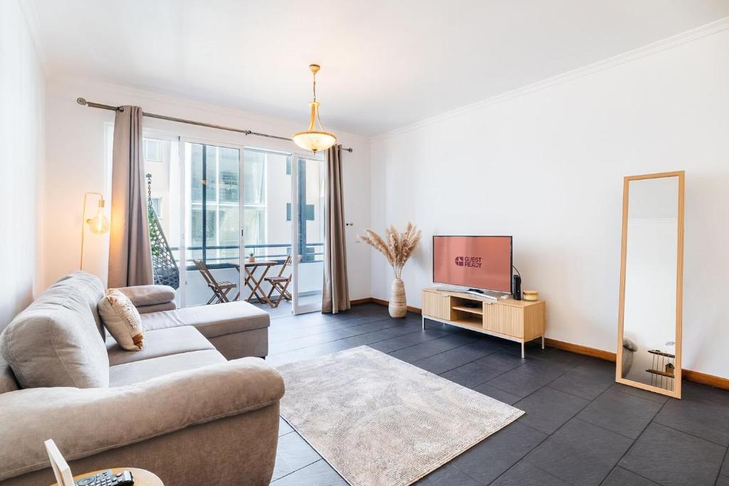 a living room with a couch and a tv at GuestReady - Charming Apartment with Ocean Views in Caniço