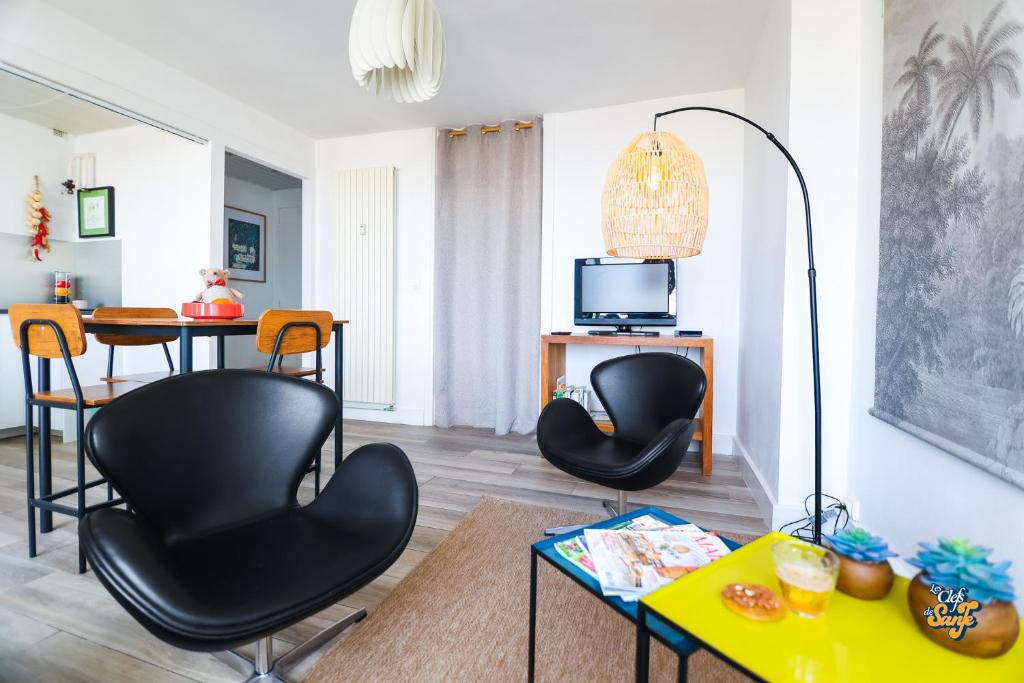 a living room with two black chairs and a table at La Loge de la Tour in Calais