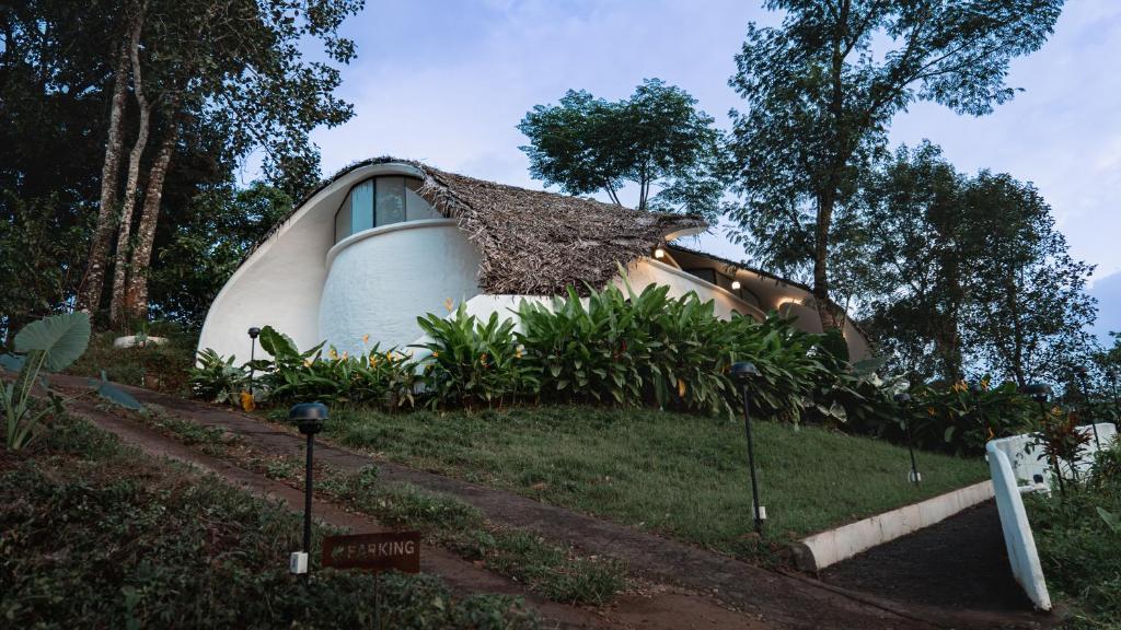 a house with a thatched roof on top of a yard at Earth's Embrace in Kalpetta