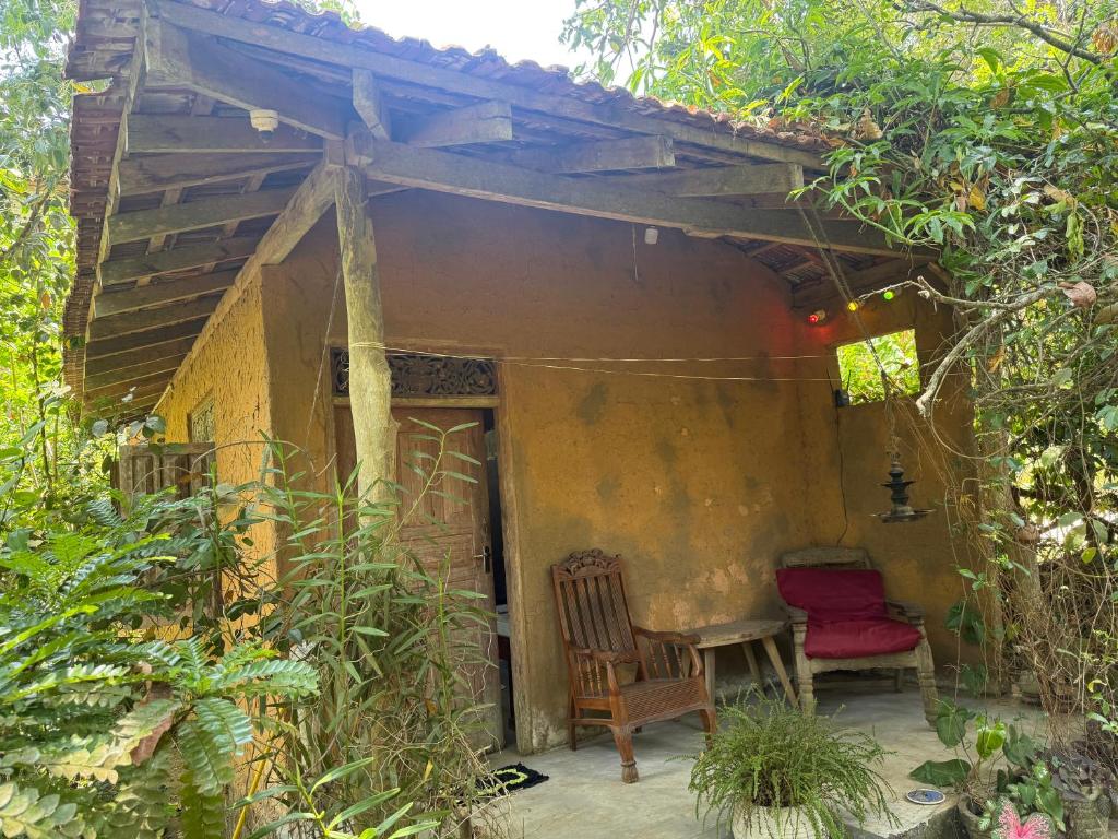 a porch of a house with a chair and a table at The Mud House in Talalla South