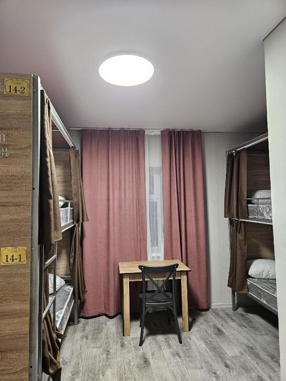 a room with a table in a room with bunk beds at Qonaq Hostel in Astana