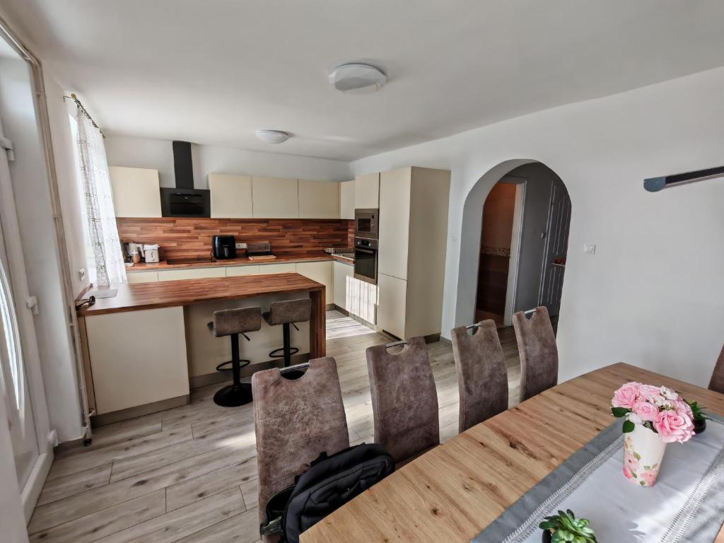 a kitchen and dining room with a wooden table and chairs at Beta Apartman in Bük