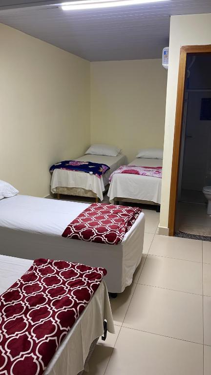 a room with three beds in a room at Pousada Centro Oeste in Trindade