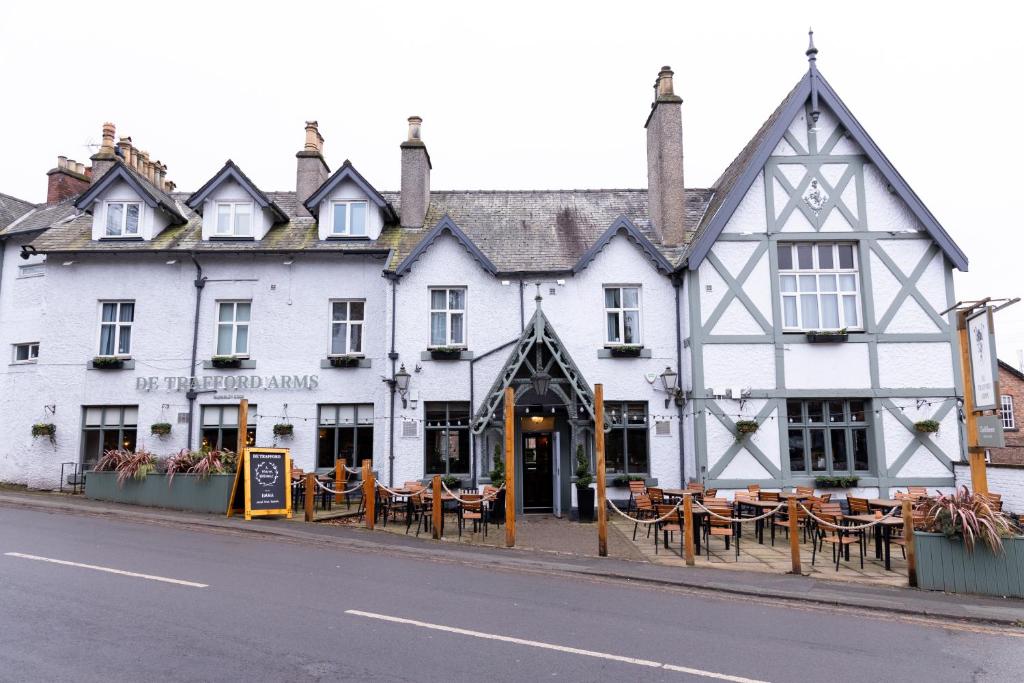 a white building with tables and chairs on the street at De Trafford Arms by Chef & Brewer Collection in Alderley Edge