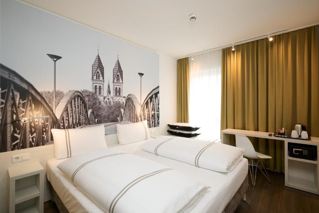 a bedroom with a large white bed and a desk at Premier Inn Freiburg City Nord in Freiburg im Breisgau