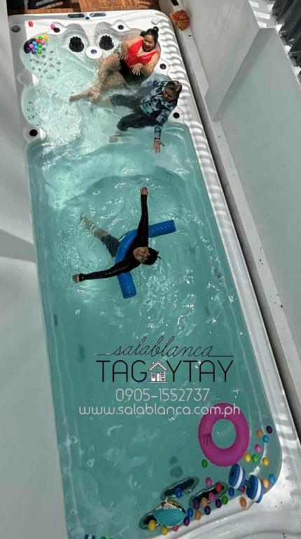 a swimming pool with two people in the water at Salablanca Brand New Jacuzzi Heated Pool PS5 VR Cinema Fully AC Indoors Smart TVs with Netflix Disney Plus Large Balcony in Tagaytay