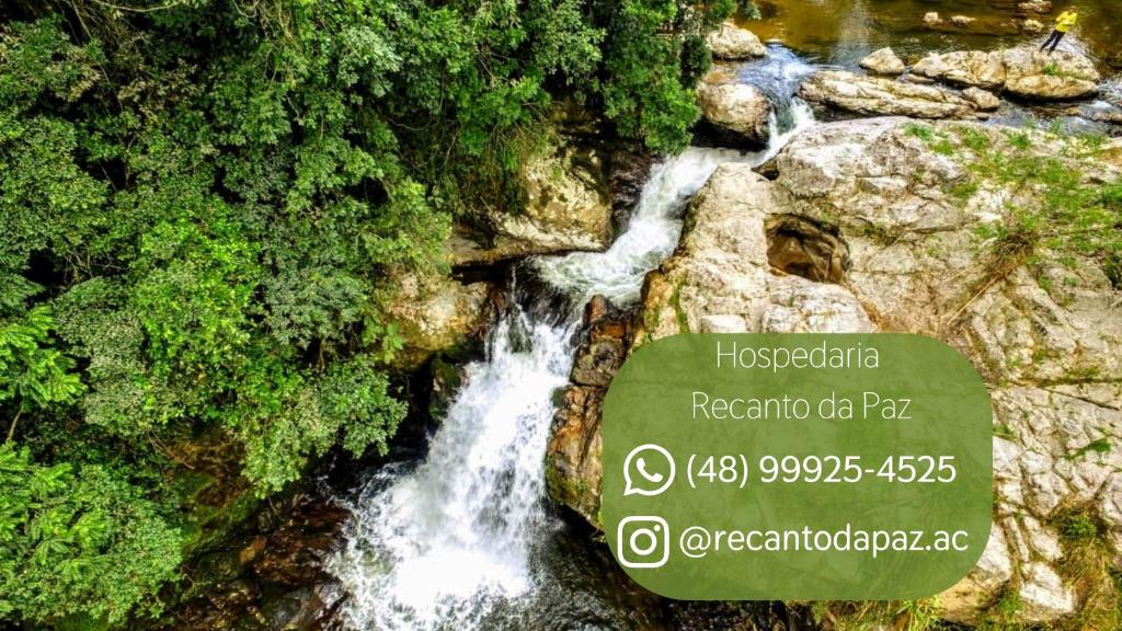a waterfall with a sign in front of a river at Suíte com Mezanino e Cachoeira no Quintal in Antônio Carlos