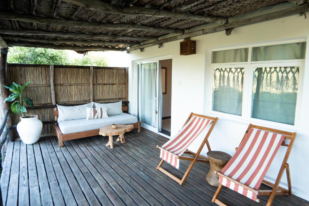 a porch with two rocking chairs and a couch at Tofo Beach Gardens in Inhambane