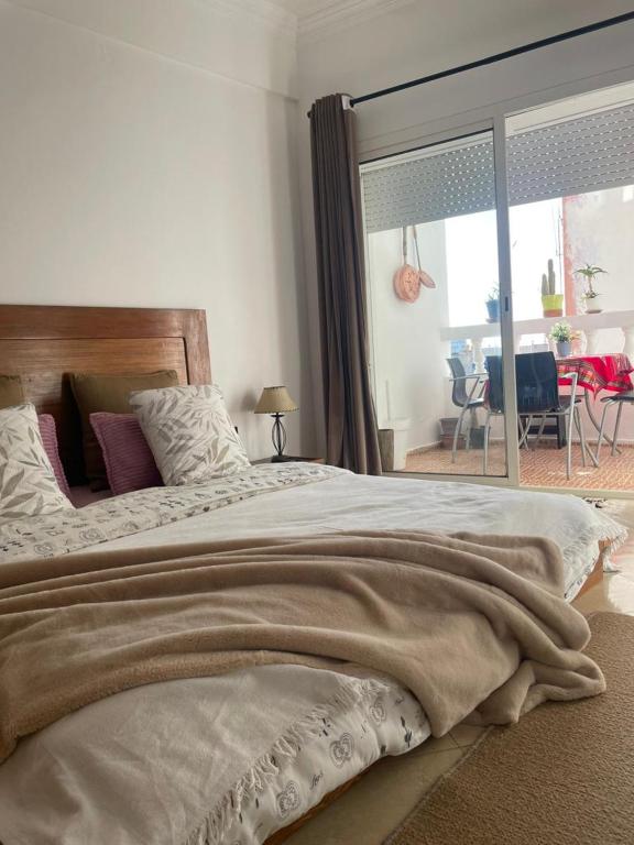 a bedroom with a large bed with a large window at Moderne appartement in Larache