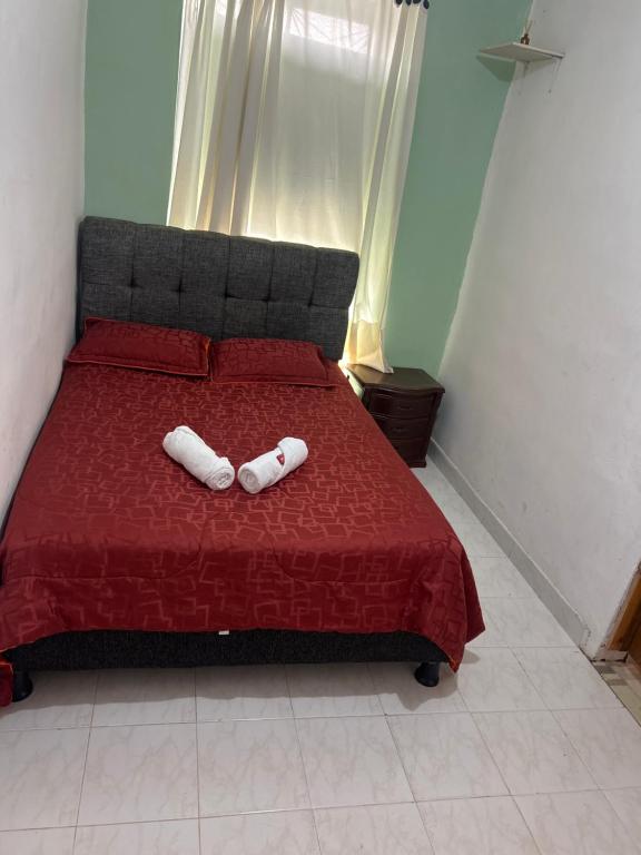 two white towels sitting on a red bed at Casa hotel Manhattan L&P in Choachí