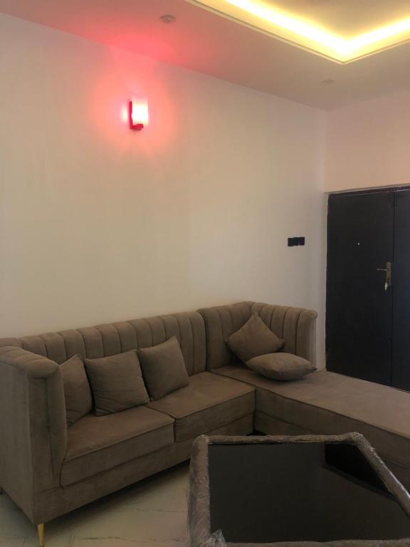 a living room with a brown couch and a red light at The 7th Haven in Uyo