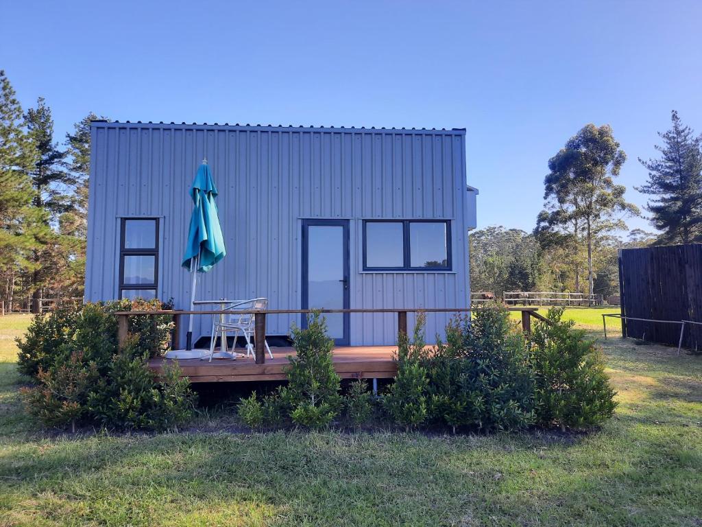 a tiny house with a table and an umbrella at Mountain view Bespoke tiny home in Plettenberg Bay