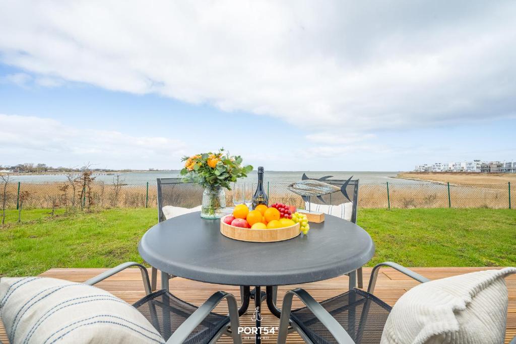a table with a bowl of fruit and a bottle of wine at Ferienwohnung Albatros Olpenitz in Olpenitz