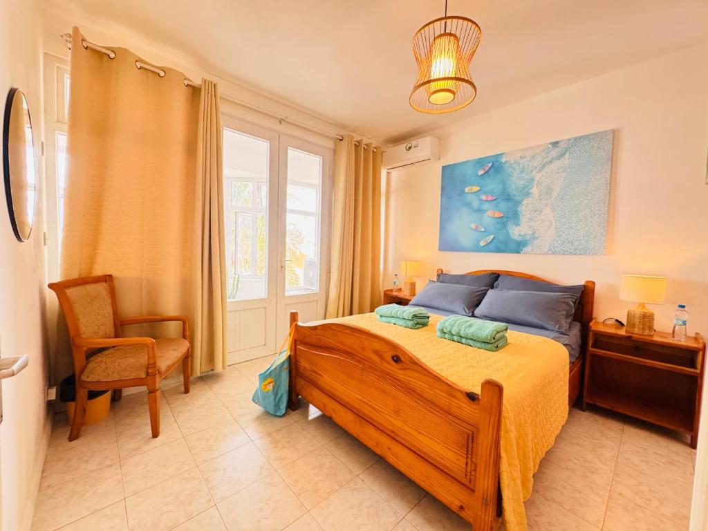 a bedroom with a bed and a chair at Fibonacci Beachfront Apartment in Flic-en-Flac