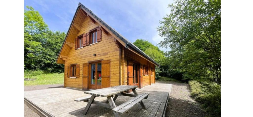a wooden cabin with a picnic bench on a deck at Chalet Ô Mont Dore in Le Mont-Dore