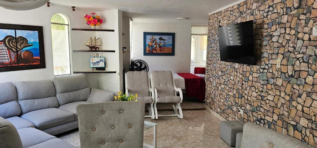a living room with a couch and a tv on a stone wall at Tu Refugio Tropical Cerca al Mar in Santa Marta