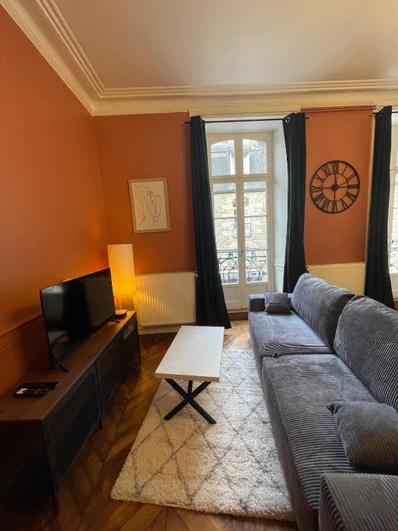 a living room with a couch and a tv at Le balcon du Beffroi in Fougères