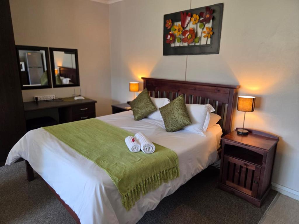 a bedroom with a bed with two slippers on it at Sekelbos Guesthouse in Pretoria
