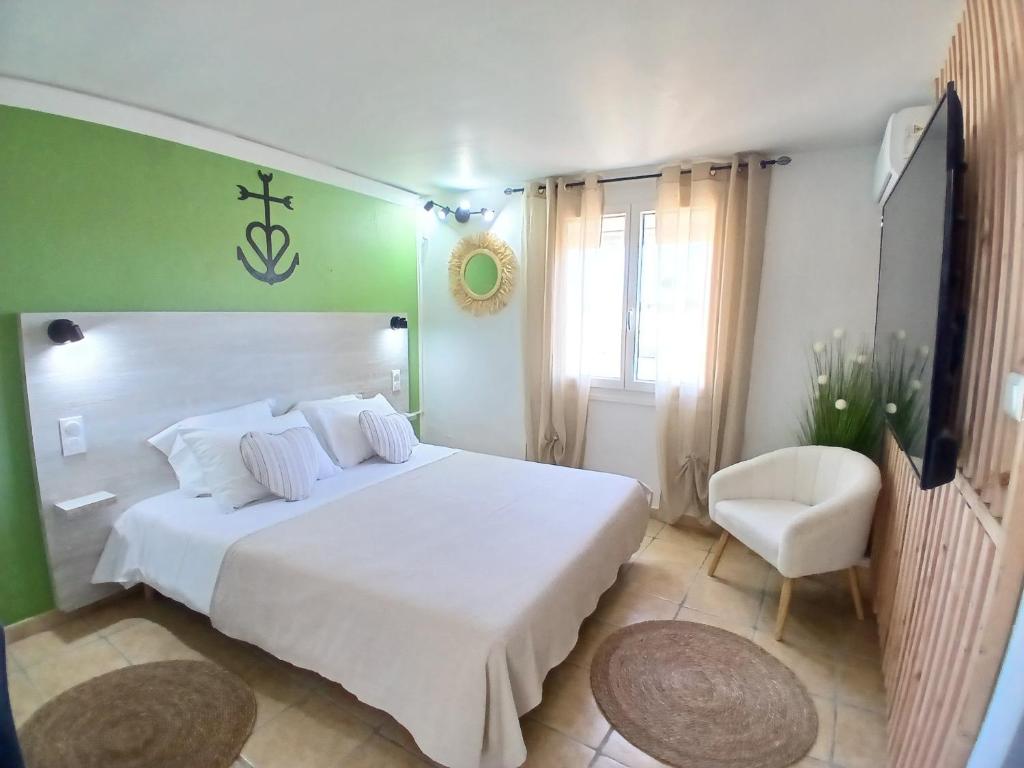a bedroom with a large white bed and a chair at Hôtel Quai d'Azur in Le Grau-du-Roi