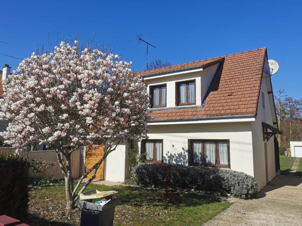 a house with a flowering tree in front of it at Le Chant des Grenouilles in Itteville