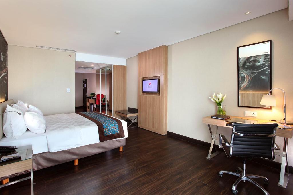 a hotel room with a bed and a desk with a computer at Swiss-Belhotel Airport Jakarta in Tangerang