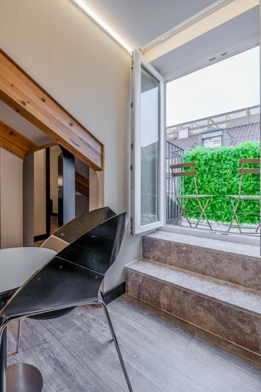 A small table and chair beside an open window, with steps leading to the raised sleeping area.
