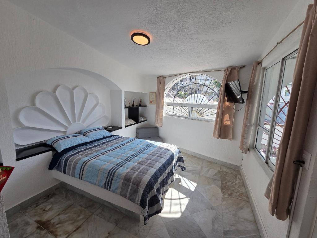 a bedroom with a bed and a large window at Casa Secretos del Sol in Acapulco