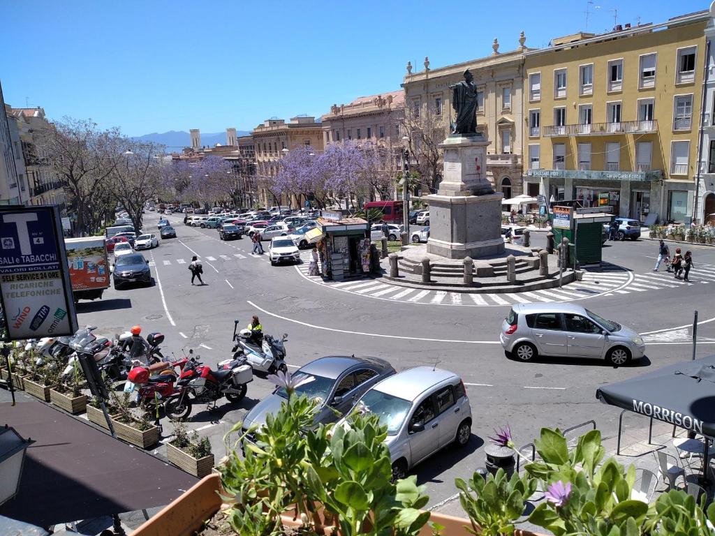 a busy city street with cars and a statue at Note Sulla Piazza in Cagliari