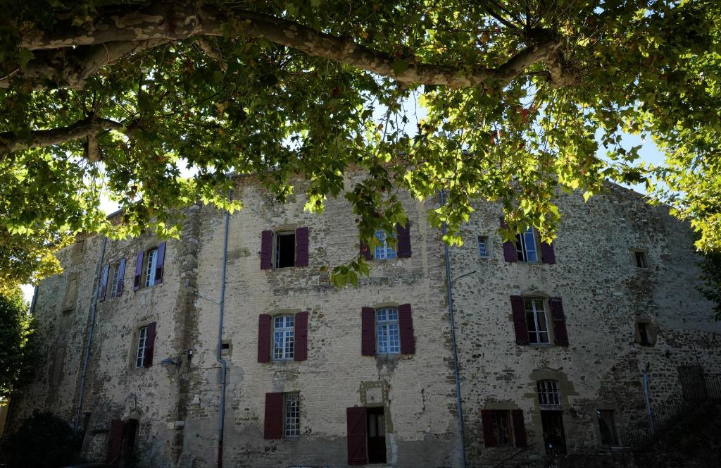 an old stone building with red shuttered windows at Château de Rosans in Rosans